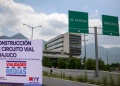Banner announcing Huajuco road circuit construction with logos beside a highway, mountains in the background, and green directional signs reading AV. LA RIOJA and SANTIAGO.